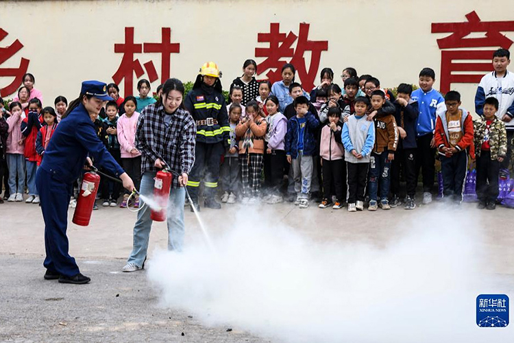 5月10日,在河南省济源市王屋镇大路小学,一名教师在消防员指导下体验用灭火器灭火。(新华社发 苗秋闹摄).jpg 5月10日,在河南省济源市王屋镇大路小学,一名教师在消防员指导下体验用灭火器灭火。(新华社发 苗秋闹摄).jpg